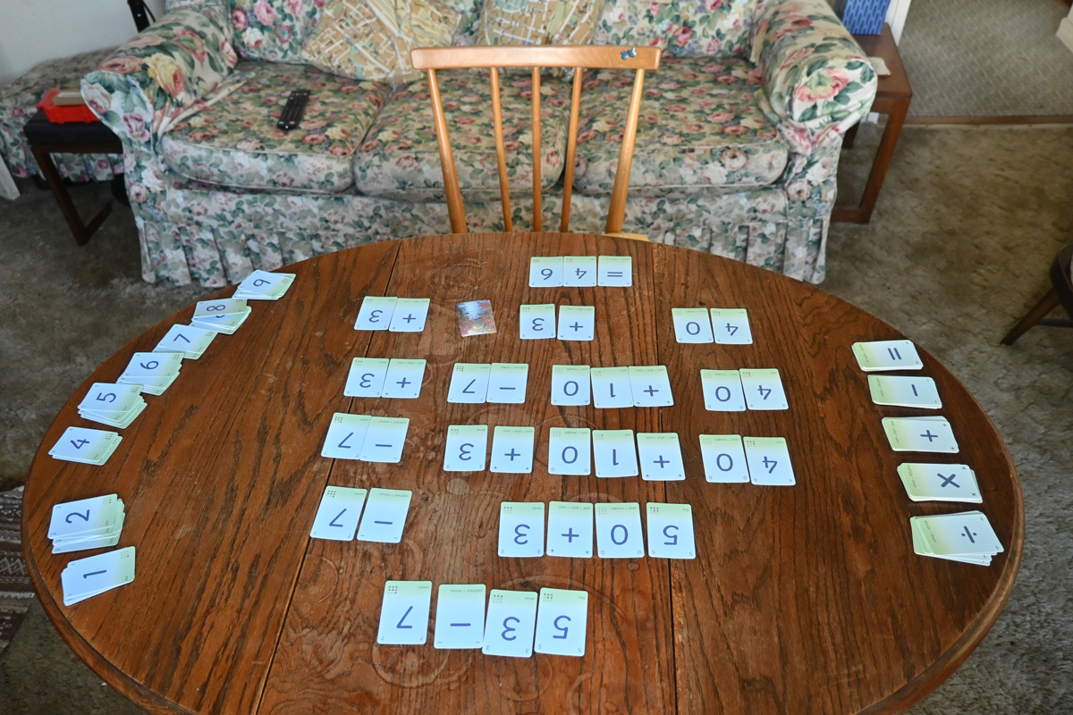 A medium sized table in a living room has numerous cards laid out. They demonstrate the need for small cards to be used.