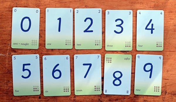 A set of Dart Cards digits are laid out on a desktop in two rows, zero to four and five to nine. For an unexplained reason the digit-eight card is face-up but upside down relative to the other cards