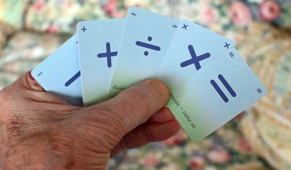 Five symbol cards are held firmly in the hand by use of the thumb.